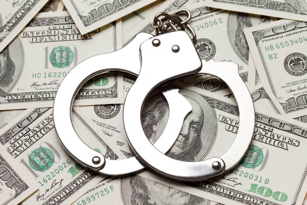 handcuffs against a background of dollar bills