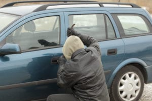 a man in a hooded sweatshirt trying to break into a car